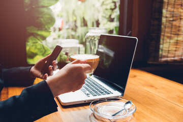 Young business woman is using his smart phone and The laptop computer in the cafe