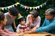 © THESHOTS.CO - Asian family celebrate kid birthday party together outdoor at yard.