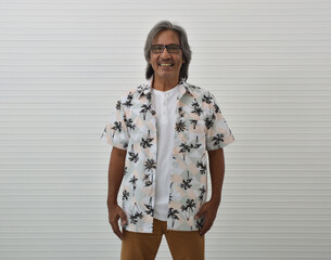 Happy senior traveler asian man wearing glasses, summer shirt and brown shorts standing over white wall background, Business summer holiday concept