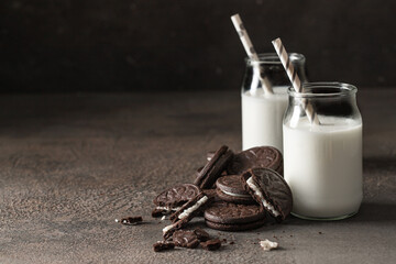 Wall Mural - Sandwich biscuits cookies filling with vanilla cream and glass of milk on dark background for breakfast concept