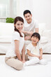 © eastfenceimage - A happy family of three sitting in couch