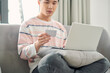 © makistock - close up of man with laptop computer and credit card at home. Young man using credit card shopping online.