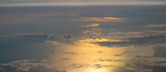 Wall Mural - clouds over the ocean illuminated by the setting sun, aerial view