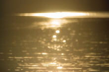 Abstract Blurry Background If Golden Water Surface At Sunset