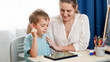 © Kyrylo Ryzhov - Smiling mother hugging and caressing her smart child studying on tablet computer. Little boy doing homework on digital tablet computer at home