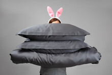 A Woman In Easter Bunny Ears Holds A Warm Duvet And Gray Feather Pillows. Bed Linen For Sleeping.