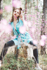 Wall Mural - Japanese-style girl in a flowering forest among pink flowers in spring