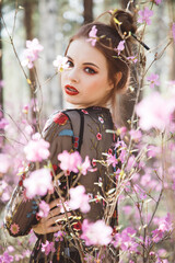 Wall Mural - Japanese-style girl in a flowering forest among pink flowers in spring