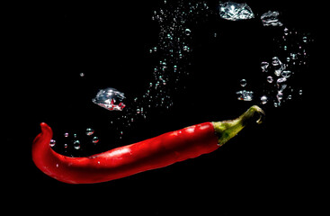 fresh red chilies with water bubbles. the concept of freshness of fruit in water. underwater vegetable photo with isolated black background