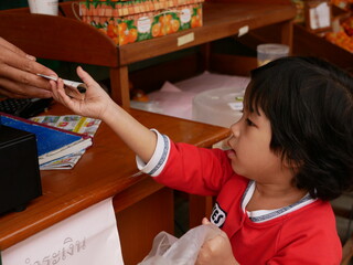 Little baby girl, 3 years old, learning to buy stuff and receive the change by herself - children development by allowing them to do things by themselves