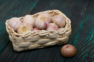 Wall Mural - Garlic in a wicker basket. On green pine boards. Close-up shot.