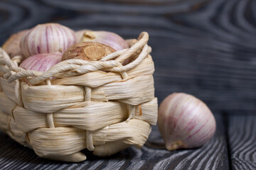 Wall Mural - Garlic in a wicker basket. Close-up shot. On black pine boards.