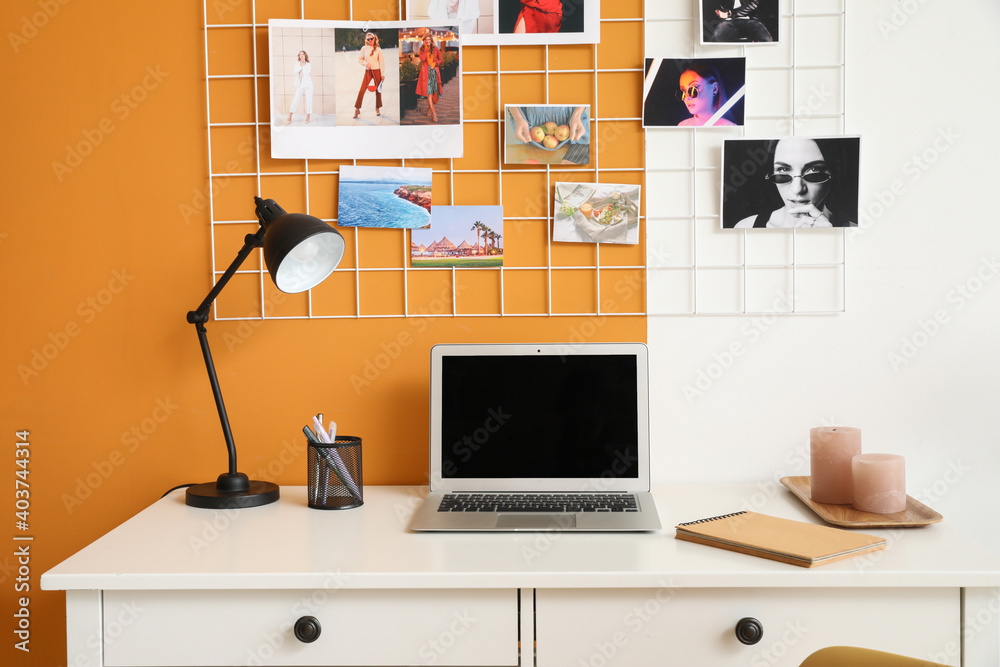 Comfortable workplace with modern laptop near color wall