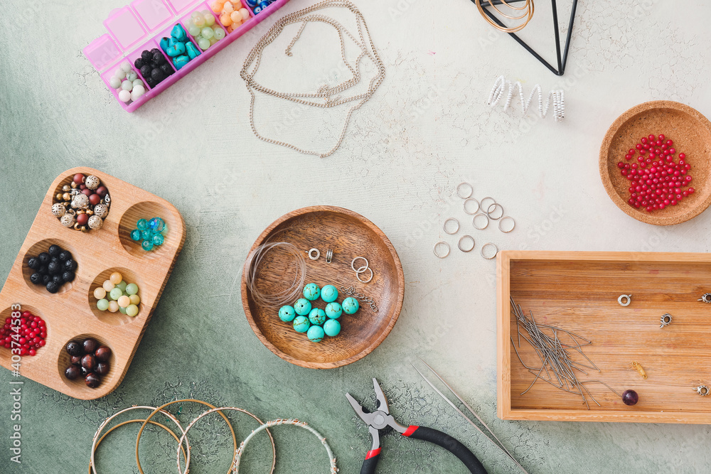 Workplace of jewelry designer with  tools and beads on light background