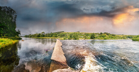 Wall Mural - Panoramic view of concrete dam on river Lee in Ballincollig Regional park in summer on cloudy day