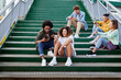 © gpointstudio - Group of young people sitting on stairs with mobile phones
