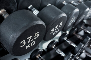 Closeup of 37.5 kilogram dumbbells placed on a dumbbell rack at the gym. Weight training equipment.