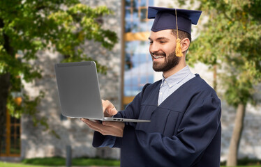 Poster - education, graduation and people concept - happy smiling male graduate student in mortar board and bachelor gown with laptop computer over university campus background