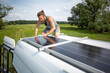 Man wiping a solar panel on top of a camper van