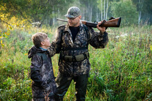Father And Son Standing Together Outdoors With Shotgun Hunting Gear.