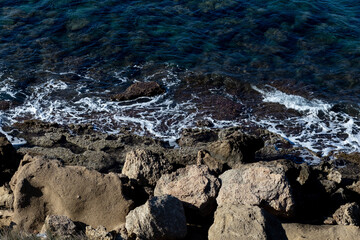 Wall Mural - Top down view of splashing waves at the rocks in the ocean or sea.