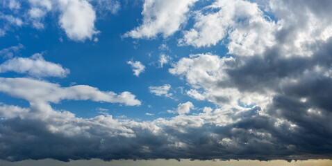 Wall Mural - storm is coming. dark gray stormy clouds covering bright blue sky with fluffy white clouds. changing