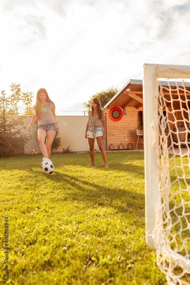 Young friends having fun playing football in the backyard - obrazy, fototapety, plakaty 
