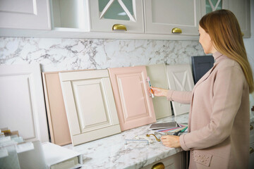 home improvement concept. girl the designer chooses the facades and handles for cabinet furniture in