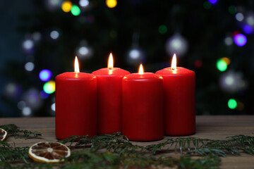 Poster - Closeup of burning red advent candles on a wooden surface, in front of colorful bokeh lights