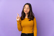 © luismolinero - Young mixed race woman isolated on purple background with fingers crossing and wishing the best