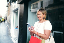 Smiling Woman Sending Messages With Her Shopping Bags