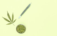 Big Marijuana Joint, Grinder Full Of Chopped Weed And Leaf On Yellow Background With Copy Space Right.