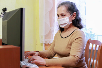 Wall Mural -  55-year-old senior woman working with face mask at home office