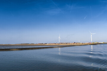 Canvas Print - Water with low waves and the white wind turbines