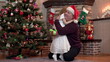 Granddaughter gives grandfather a Christmas present and kisses and hugs him by the tree
