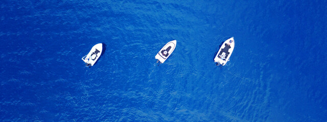 Wall Mural - Aerial drone ultra wide top down photo of synchronised powerboats cruising in high speed in deep blue open ocean sea