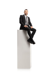 Poster - Man in a suit and tie sitting on a tall white column and smiling at camera