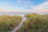 Fototapeta Paryż - sand path trough the dunes towards the ocean under the beautiful sunset sky