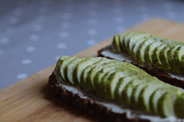 Avocado sandwich on a wooden board.  Avocado and black bread.