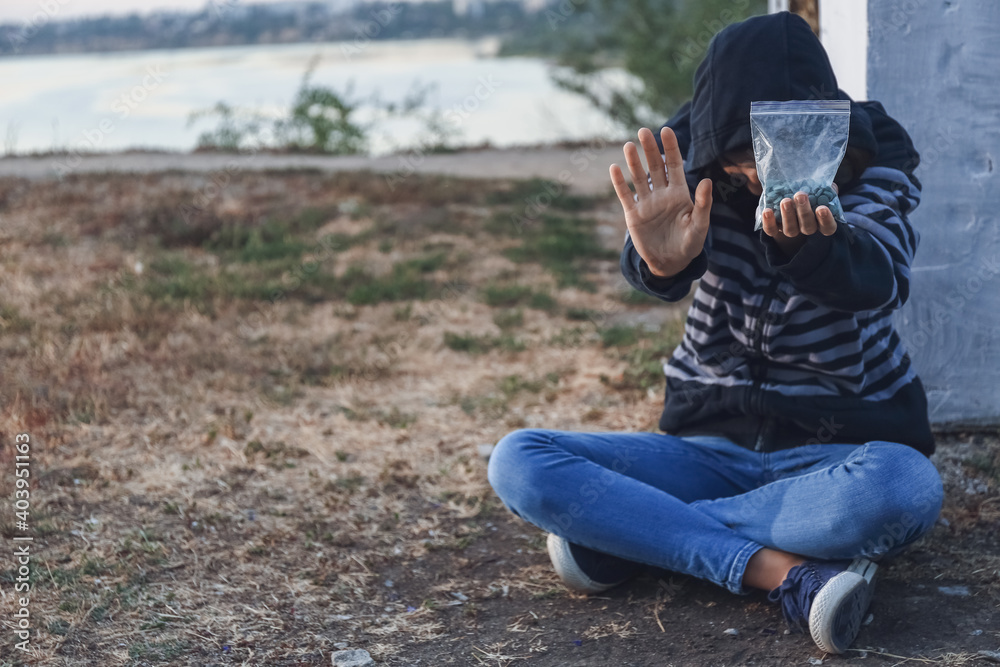 Female junkie showing STOP gesture outdoors