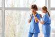 © Pixel-Shot - Female doctor calming her colleague in clinic