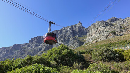 the funicular ascends table mountain in cape town. against the background of the blue sky, cables, a