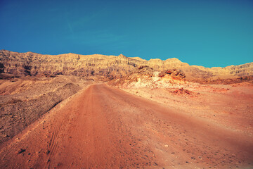 Fototapete - Driving a car on a dirt road in the desert. View of the sandstone mountains through the windshield. Timna Park, Israel