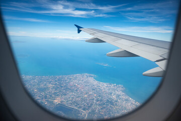 Aircraft Wing on beautiful blue sky and cloud background. In altitude during the flight over the sea of Pattaya Thailand. Wing of an airplane looking from the window.