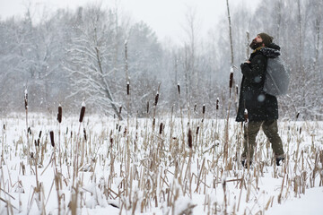 Outdoor portrait of handsome man in coat and scurf. Bearded man in the winter woods.