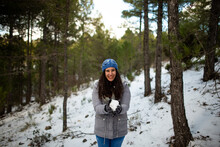 Pretty Brunette Woman Enjoying The Snow On The Snowy Mountain With Blue Hat And Winter Coat