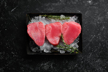 Wall Mural - Raw tuna steak with spices on ice. On a dark background. Top view.