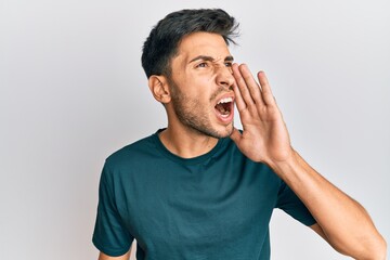 Wall Mural - Young handsome man wearing casual clothes shouting and screaming loud to side with hand on mouth. communication concept.