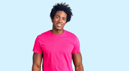 Wall Mural - Handsome african american man with afro hair wearing casual pink tshirt looking positive and happy standing and smiling with a confident smile showing teeth