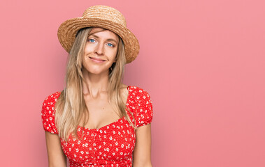 Sticker - Beautiful caucasian woman wearing summer hat relaxed with serious expression on face. simple and natural looking at the camera.